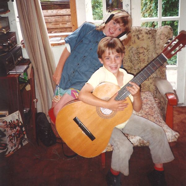 9 year old Chris holding an acoustic guitar, sister Laura behind