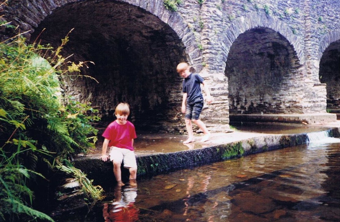 Chris with brother Des, playing in a river under a bridge